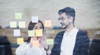 Man and woman discussing ideas written on colourful post-it notes